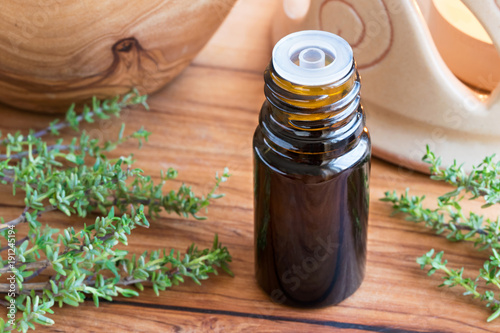 A dark bottle of thyme essential oil with fresh thyme twigs