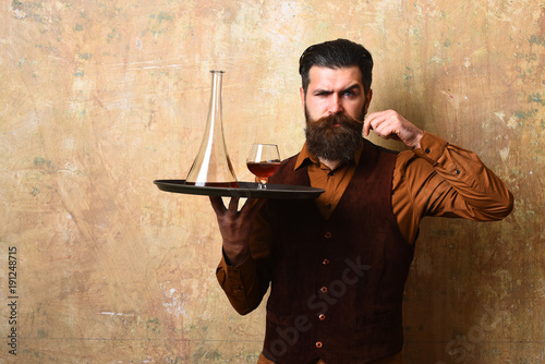 Man with beard curls mustache holding cognac photo