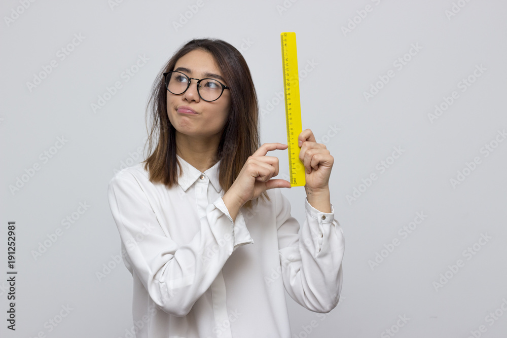 Indoor portrait of young asian woman showing small values on yellow ruler. Student life concept. Selective focus and shallow DOF Indoor portrait of young asian woman showing small values on yellow ruler. Student life concept. Selective focus and shallow DOF