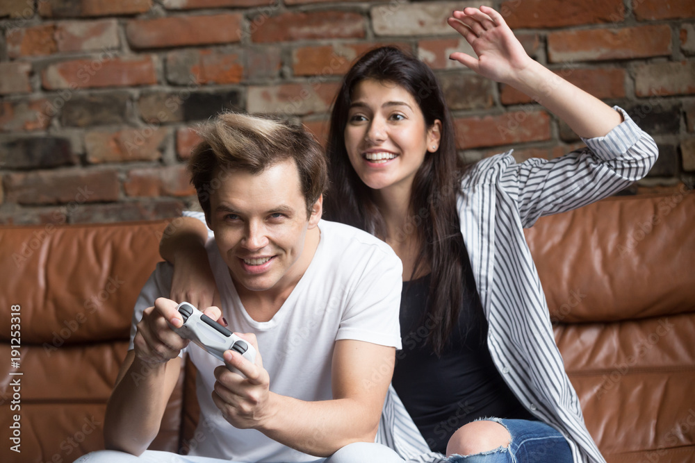 Happy boyfriend and girlfriend playing video games and holding