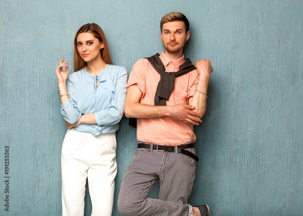 .Fashion girl and guy in outlet clothes posing on a blue background