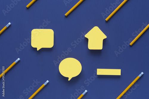 Blank post-it notes surrounded by pencils - Wooden pencils with eraser tops arranged parallelly and only  one in horizontally, out of context, with space for text, on a purple background. photo