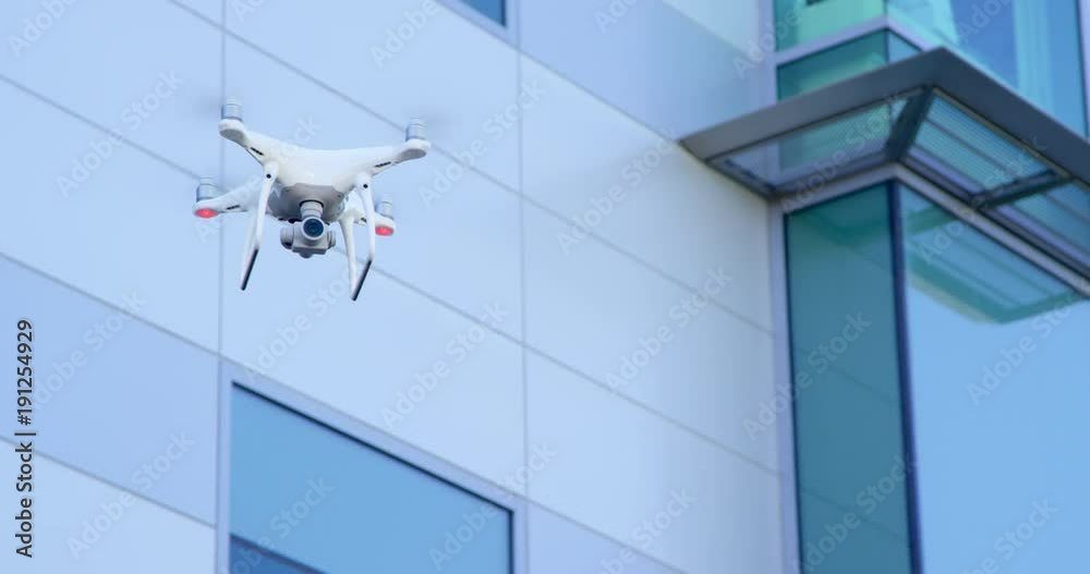Modern drone quadcopter flying with business building in background 