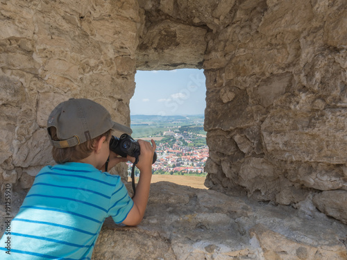 Kid watching through hole in stone wall