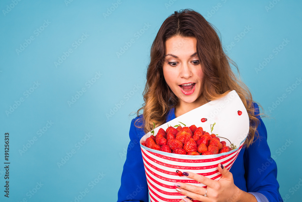 Bouquet of strawberries in the hands of a girl on blue background Bouquet of strawberries in the hands of a girl on blue background