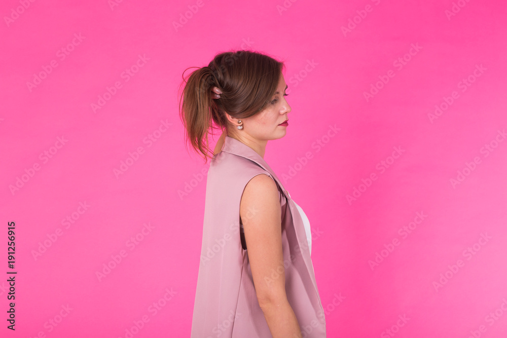 Pretty stylish girl with long hair posing against pink background. Fashion portrait of young happy smiling woman Pretty stylish girl with long hair posing against pink background. Fashion portrait of young happy smiling woman