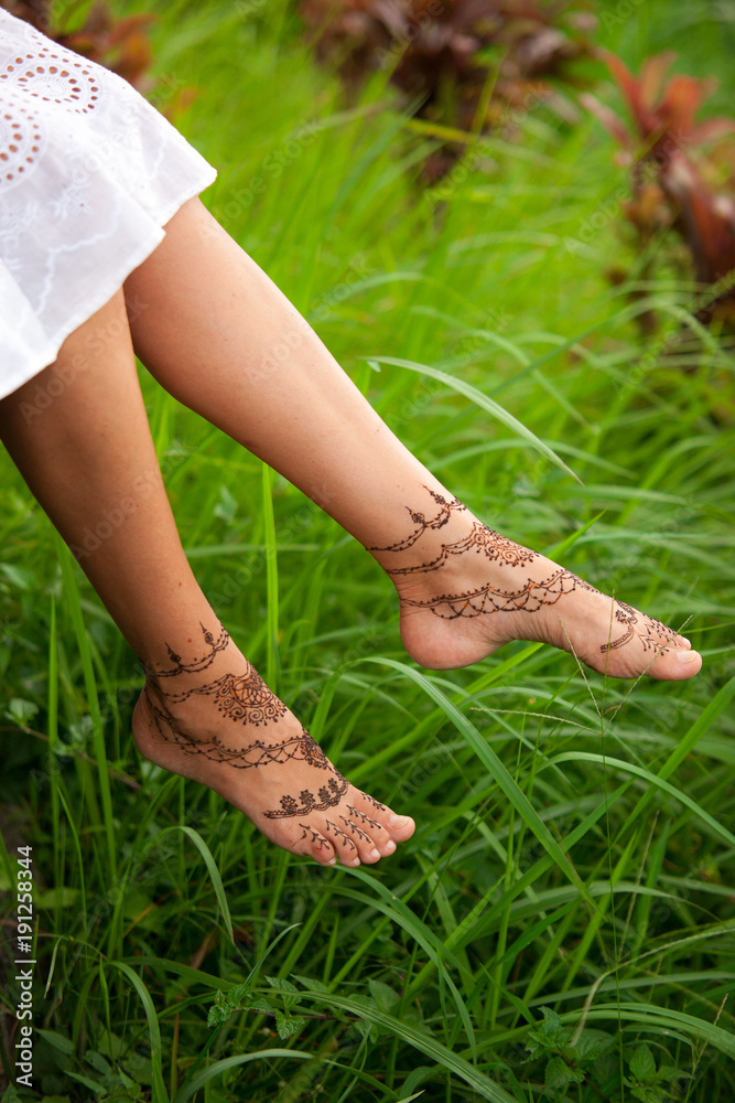 Henna tattoo design on legs. Beautiful indian mehendi ornaments painted on a body part. Carefree summer holiday concept.