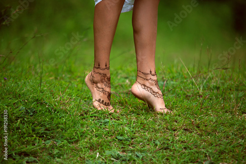 Henna tattoo design on legs. Beautiful indian mehendi ornaments painted on a body part. Carefree summer holiday concept.