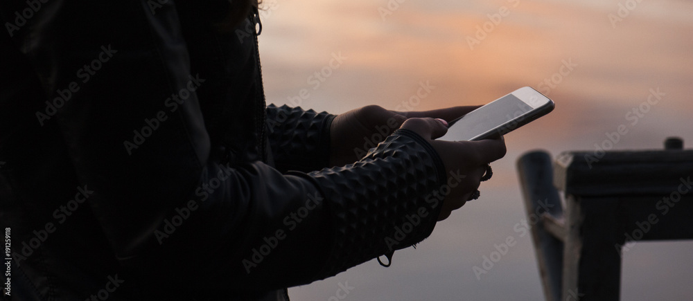Φωτογραφία The panorama of  woman is standing near the water, using smart phone and waiting