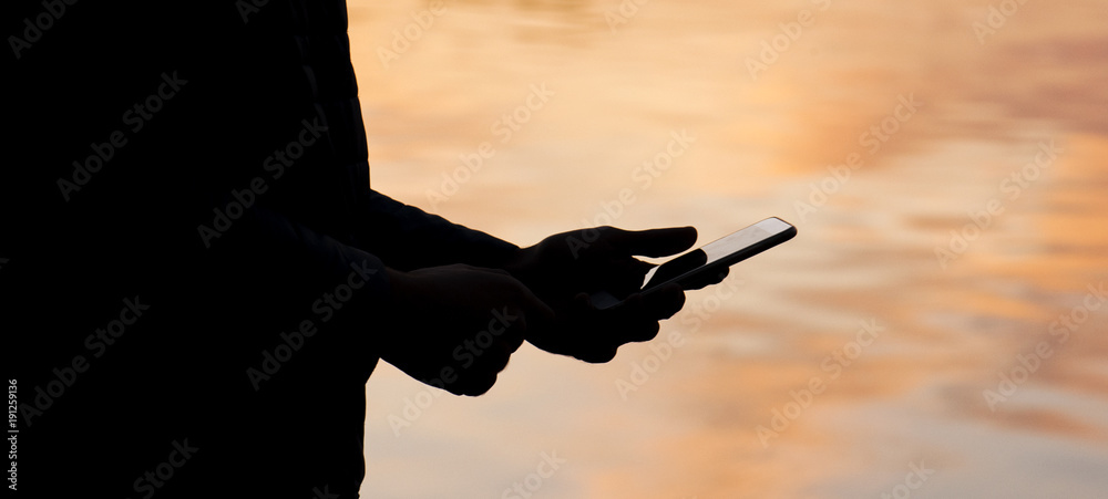 Φωτογραφία The panorama of  woman is standing near the water, using smart phone and waiting