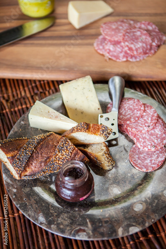 Happy Hour Snack of Meat, Cheese, Mustard, Bread on dark plate