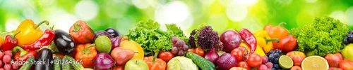 Panel kuchenny z motywem Panorama of fresh vegetables and fruits on blurred background of green leaves.