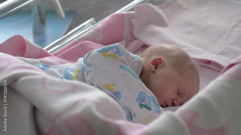Slow motion shot of a mother covering sleeping newborn baby girl with pink blanket. First days in maternal hospital Slow motion shot of a mother covering sleeping newborn baby girl with pink blanket. First days in maternal hospital