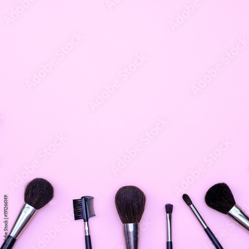 Set of makeup brushes on pink colored composed background. Top view point, flat lay, space for text.