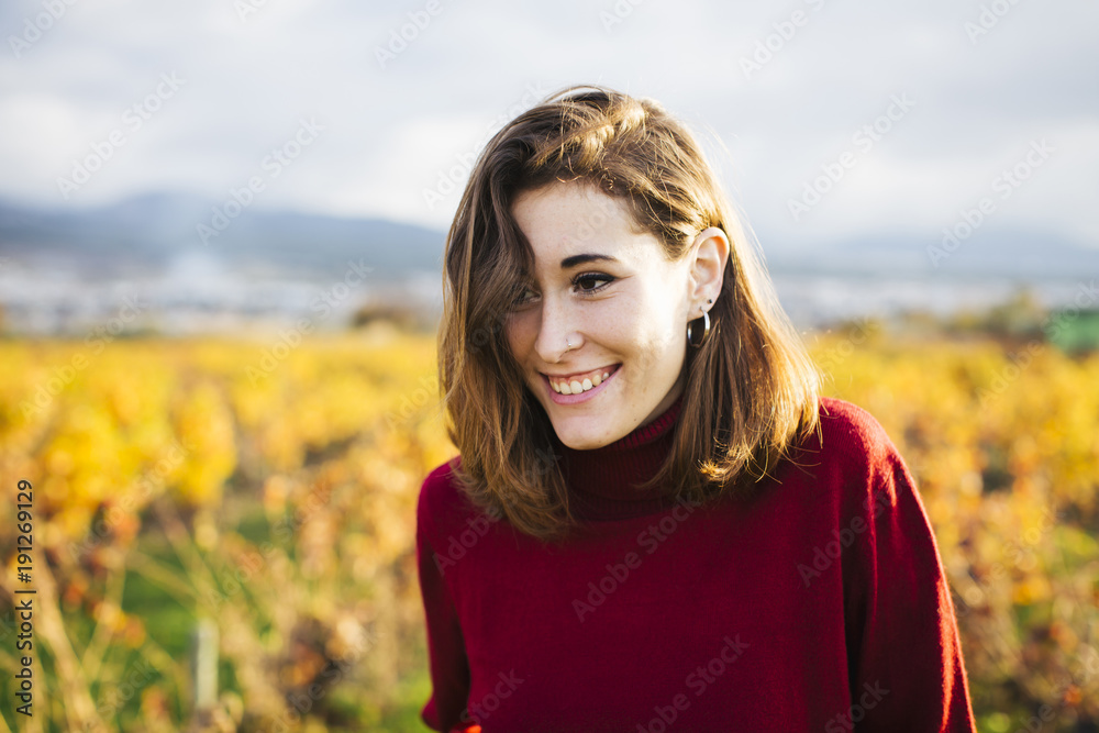 Young beautiful girl in the field. She wears a red sweater and jeans.