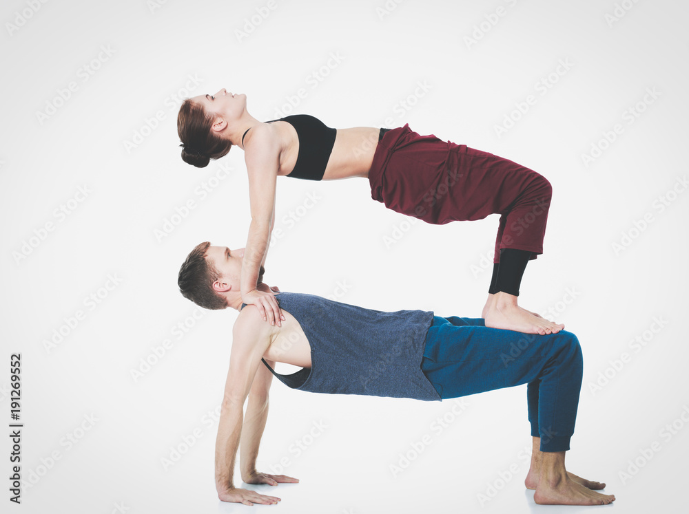 Naklejka premium Young athletic couple practicing acroyoga. Balancing in pair