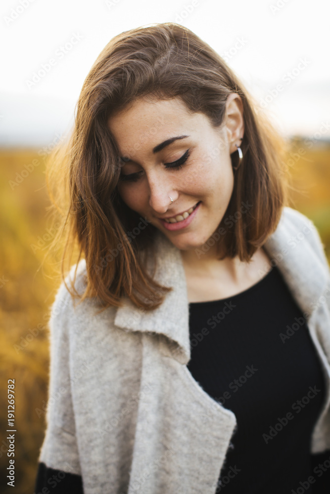 Young beautiful smiling girl in the field. She wears a sweater and jeans. Yellow background. Young beautiful smiling girl in the field. She wears a sweater and jeans. Yellow background.