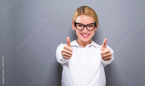  Happy young woman giving thumbs up on a solid background