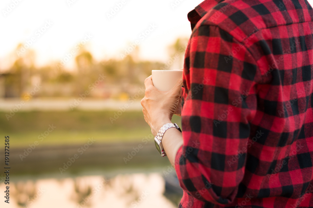 Man hold coffee cup in hand stand alone near the lake with morning light selective focus, copy space. Man hold coffee cup in hand stand alone near the lake with morning light selective focus, copy space.