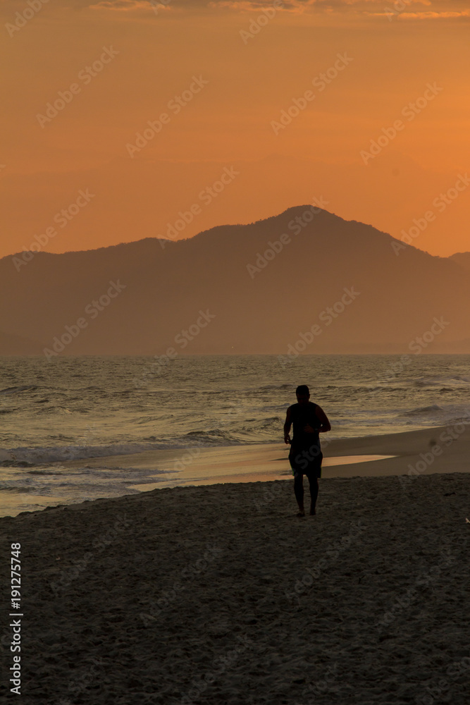 Silhouette of a man running on the beach during sunset