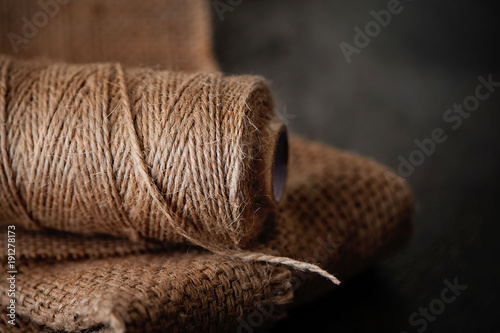 Natural jute twine roll, burlap on black background. Supplies and tools for handmade hobby leisure