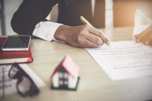 Close up of Business man pointing and signing agreement for buying house. Bank manager concept.