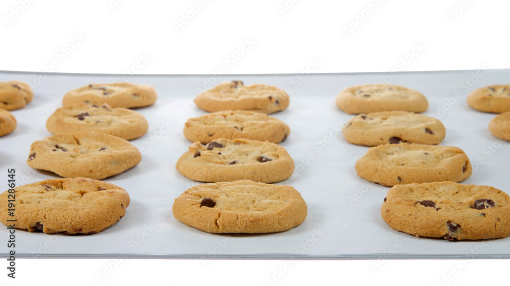 Soft and chewy chocolate chip cookies on a baking tray lined with parchment paper. A popular homemade treat for adults and children alike.