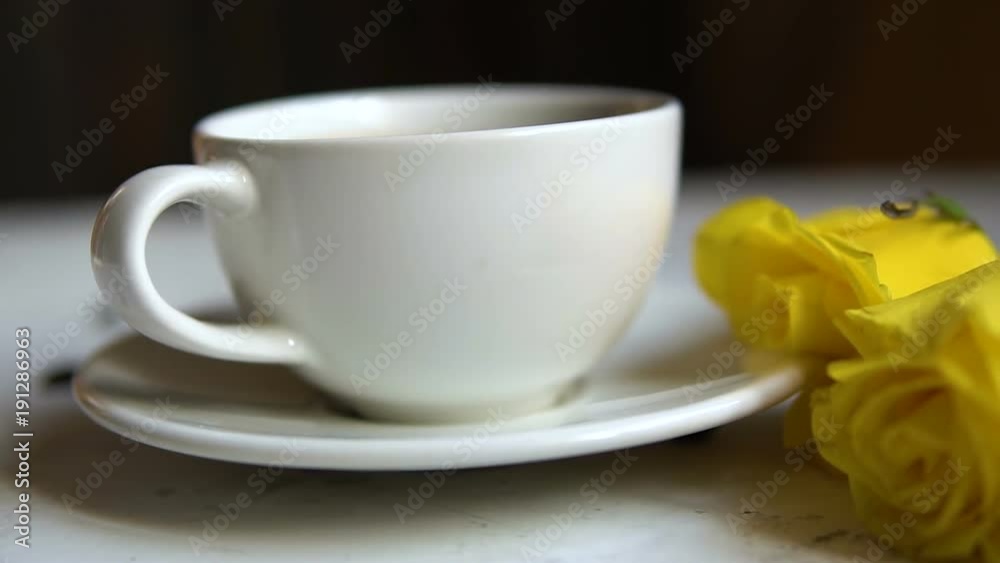 Black coffee in a white cup and yellow roses on the table. Black coffee in a white cup and yellow roses on the table.
