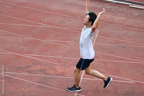 Athletic Asian runner sprinter crossing the finish line. © tuaindeed