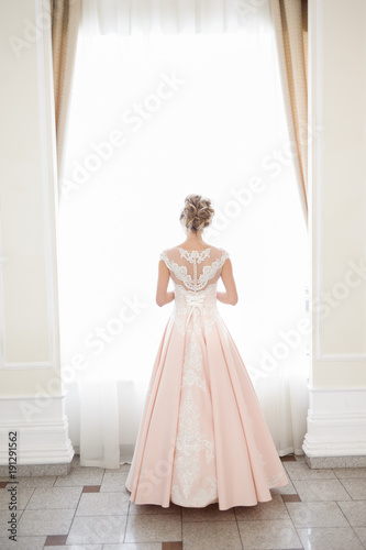 A beautiful woman in a pink wedding dress in a big festive hall