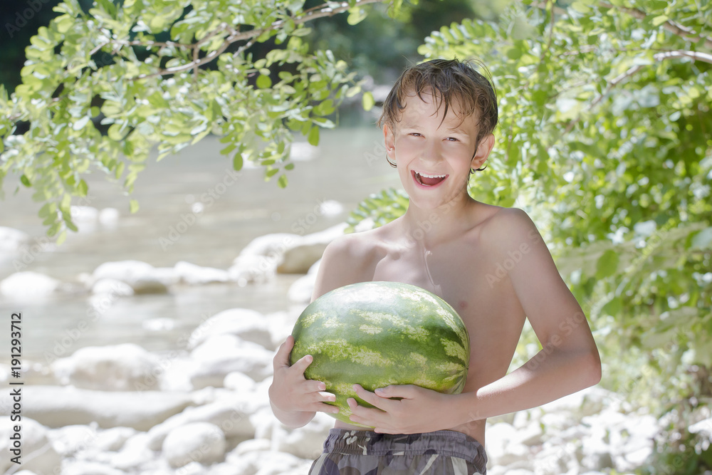 Fototapeta premium Teenager boy holding fresh green watermelon in his hands