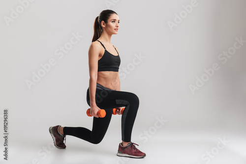 Картината върху платно Photo of sporty caucasian woman squatting with small weights, isolated over gray