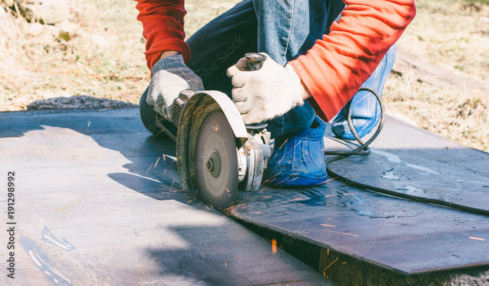 Obraz premium welder cuts metal sheet by angle grinder machine