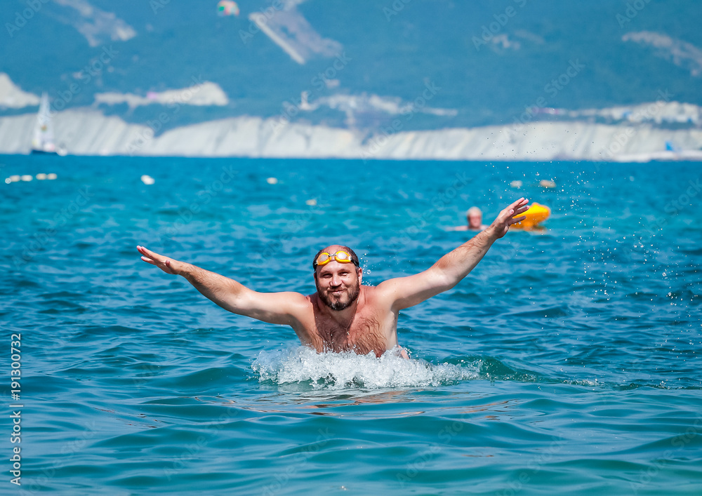 Sports training of a swimmer in the sea with mountains in the background