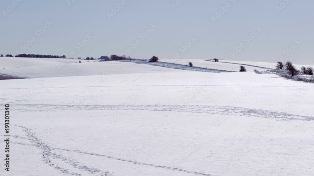 Flying over snow covered farmland in winter on a bright day Flying over snow covered farmland in winter on a bright day