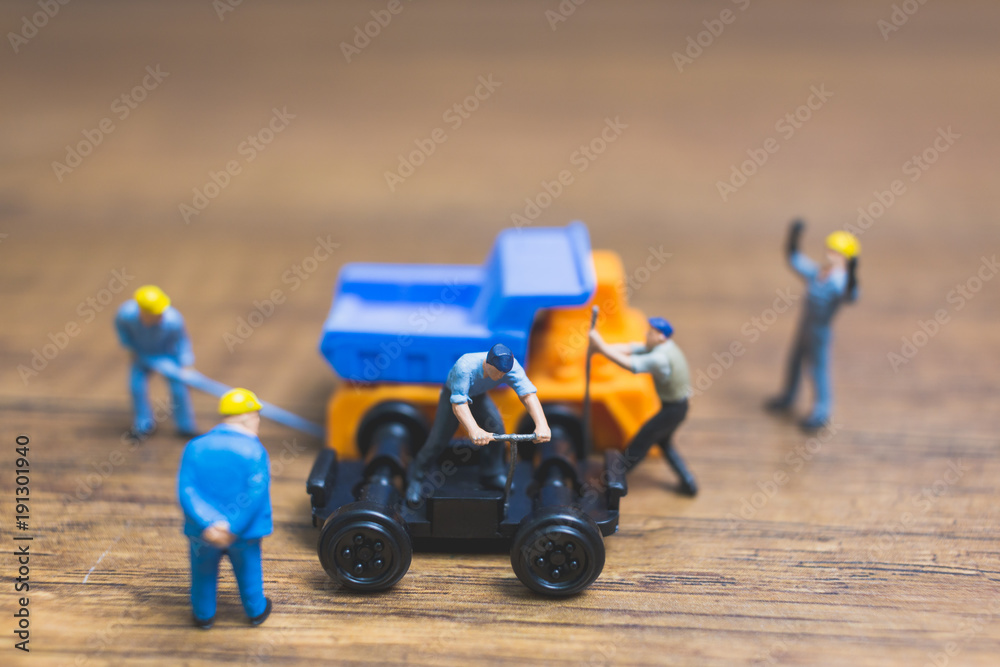 Obraz premium Miniature people : Worker repairing wheel of a truck