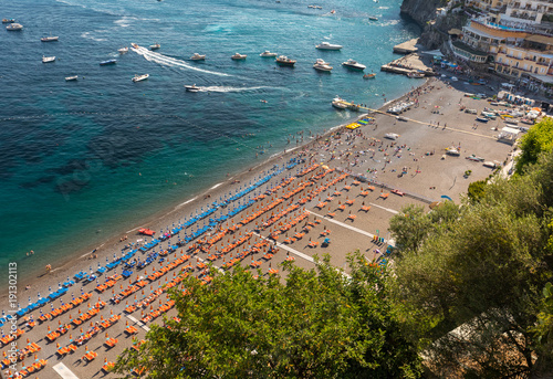 Fototapeta Naklejka Na Ścianę i Meble -  The main beach in Positano, Spiaggia Grande, with its bright orange and blue beach umbrellas and the sparkling blue sea of the Amalfi Coast.