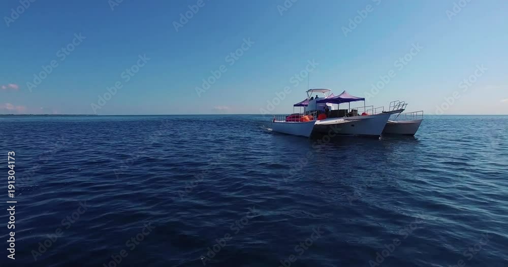 Young people ride on a catamaran boat at sea bay - Aerial view 4k. Cebu Young people ride on a catamaran boat at sea bay - Aerial view 4k. Cebu