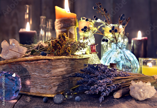 Old witch book with lavender flowers, crystal and evil candles. Occult, esoteric, divination and wicca concept. Halloween background with vintage objects 