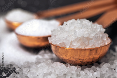 Фотография Three copper spoons with coarse salt close up.