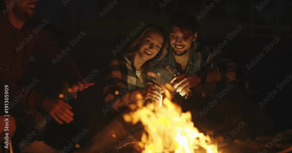 Couple enjoying with friends and drinking beer at night at beach Couple enjoying with friends and drinking beer at night at beach