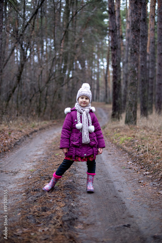 Little cute little girl posing on the road in the autumn forest.