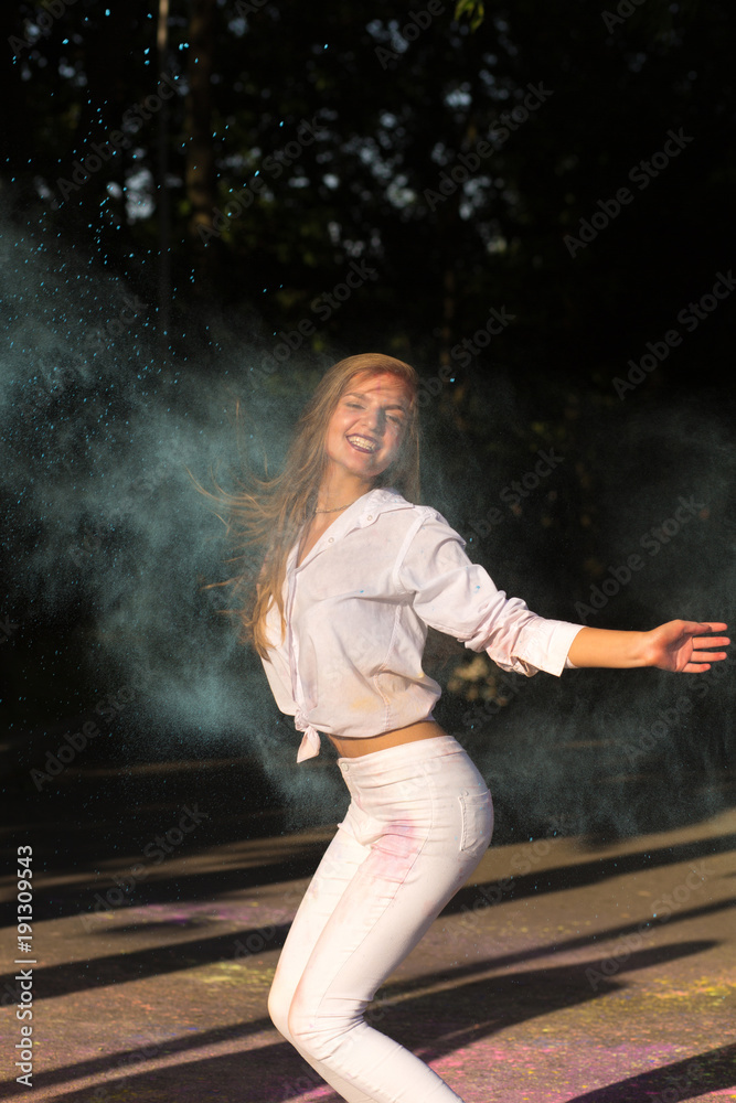 Cheerful blonde woman with long hair jumping in the park on Holi festival Cheerful blonde woman with long hair jumping in the park on Holi festival