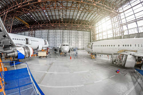 Three passenger aircraft on maintenance of engine and fuselage repair in airport hangar.