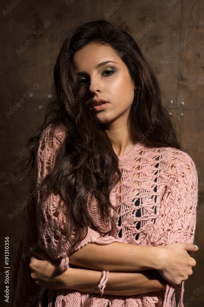 Fototapeta premium Sexy brunette model with long lush hair and professional makeup posing at the dark background