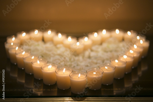 Heart created by combination of candles with white petals in the center. Romantic mood. photo