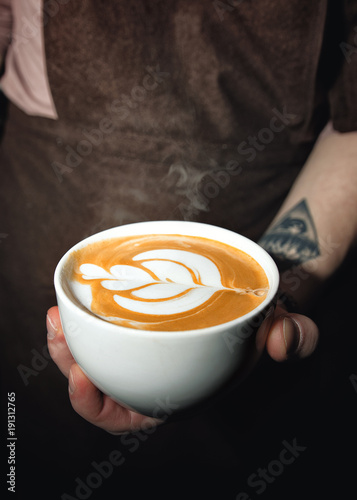 A Cup of freshly made coffee in the hands of a Barista