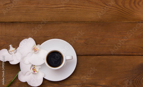 cup of coffee and white orchid flowers on a wooden brown table