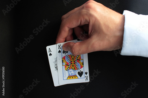 Man's hand holds a poker cards. Poker concept on black background. Close up. 