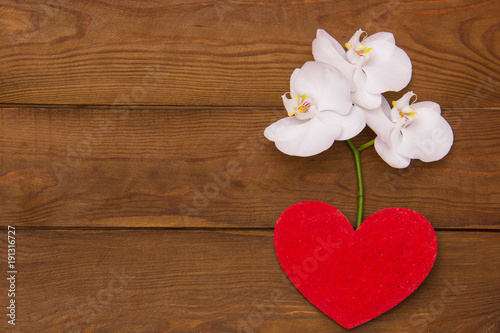 Fototapeta Naklejka Na Ścianę i Meble -  white orchids in a heart vase lie on a wooden table